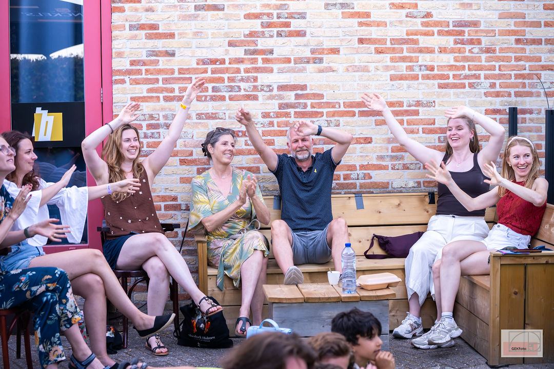 Groep bezoekers op een bankje steekt lachend de handen in de lucht — foto: GEKfoto