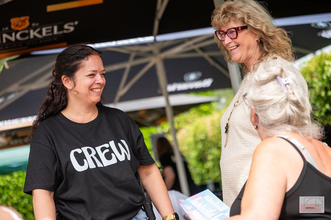 Crewlid en bezoeker lachen samen op het festivalterrein — foto: GEKfoto
