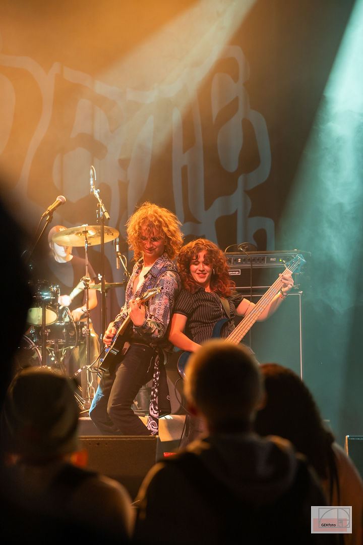 Publiek van dichtbij, met de band op het podium daarachter — foto: GEKfoto
