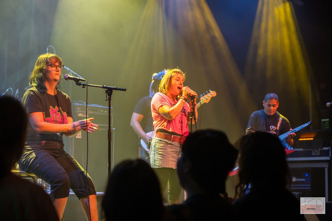 Publiek in silhouet voor een band in geel en blauw podiumlicht — foto: GEKfoto